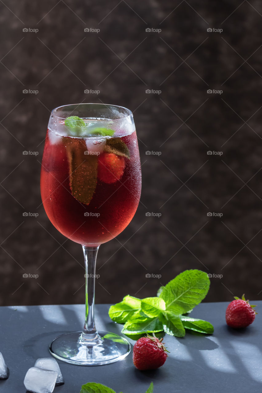 Refreshing drink with strawberries and mint on a table. Perfect for party or hot days.
