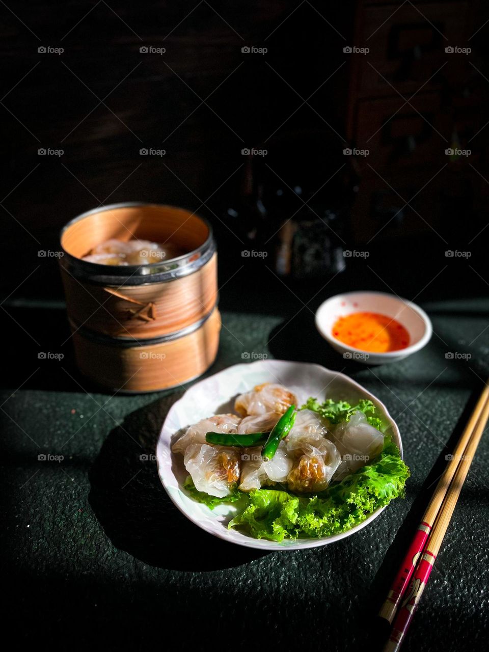 Crystal shrimp dumplings with spicy sauce on a dark table