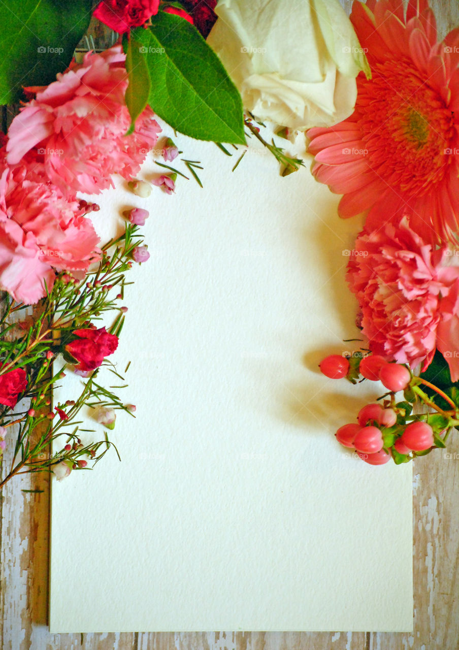 Spring, flowers, floral border, flower border, flat lay, white paper, wooden background, pink flowers and leaves, carnations, portrait orientation