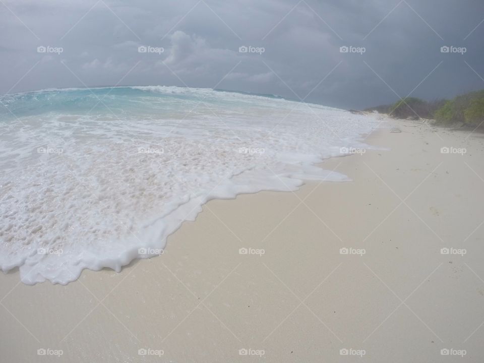 sea water foam in a beach during a cloudy day