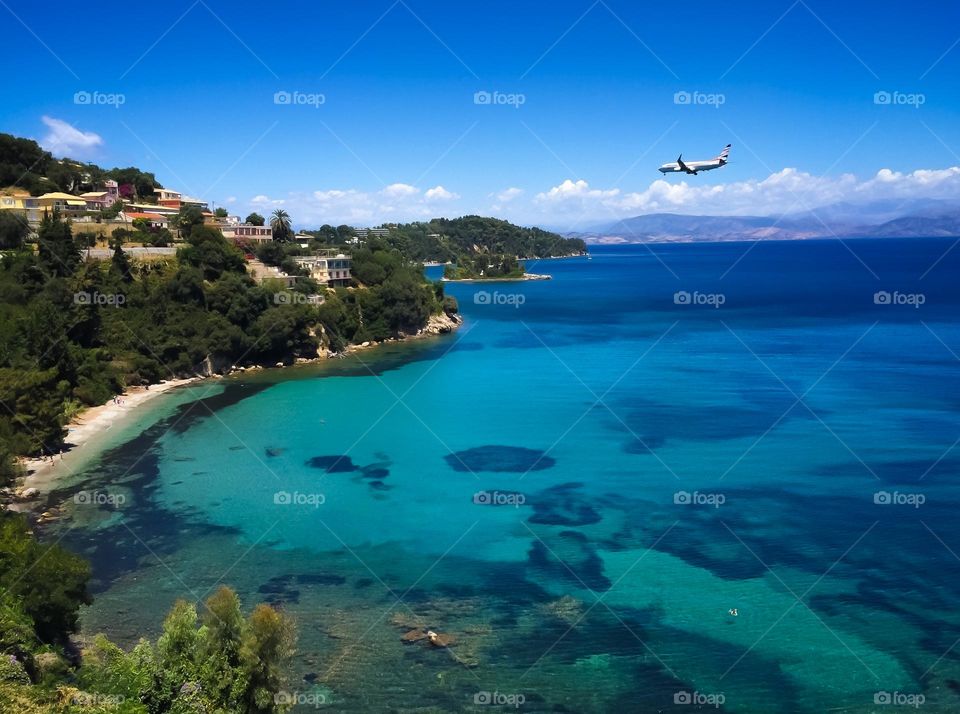 Background of Corfu with turquoise clear water and  a big plane flying to the island