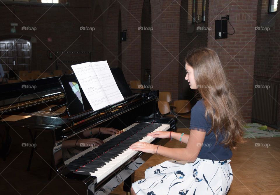 teenage girl playing the piano in the concert hall, hobby, playing music on the instrument

