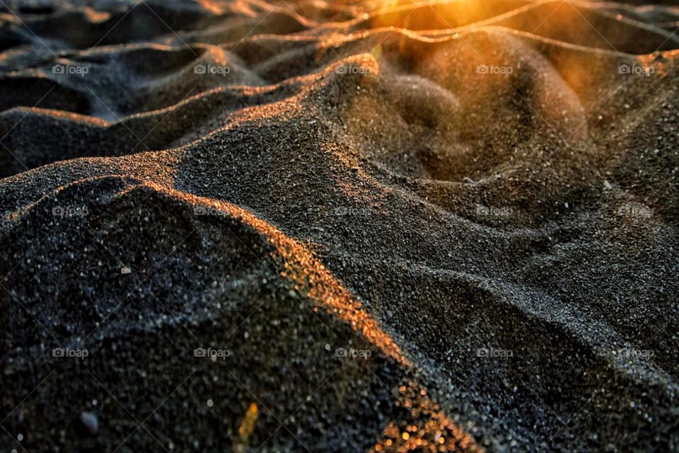 Black volcanic sand on La Palma beach in golden hour evening light 