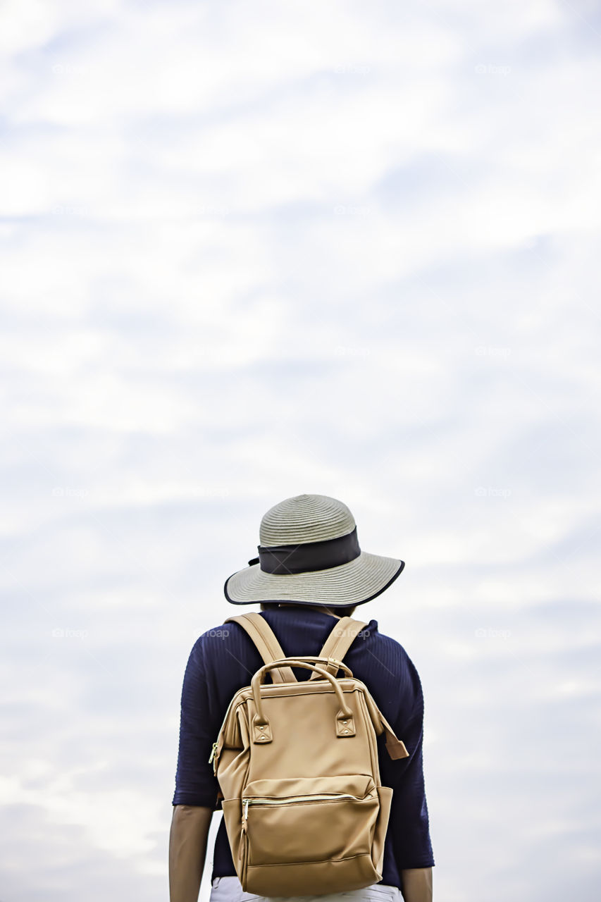 Women shoulder backpack and Wear a hat Background sky.