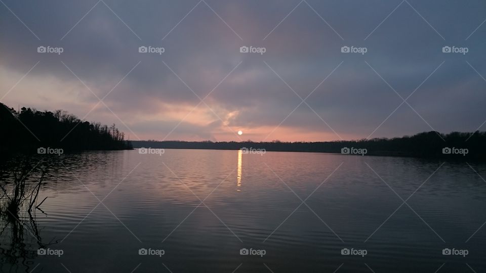 Sunset with reflecting sun and sky in the lake.