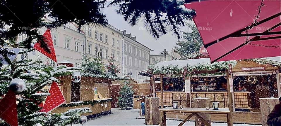 The „Christkindlmarkt“, a Christmas market held every year in „Straubing“ in „Bavaria“, Germany can be seen and through the trees the facades of several buildings in the inner city historical town square. 2022. Hypnotic Productions
