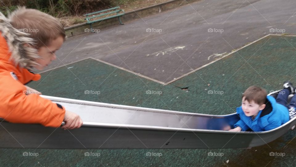 Two boys playing slide in playground