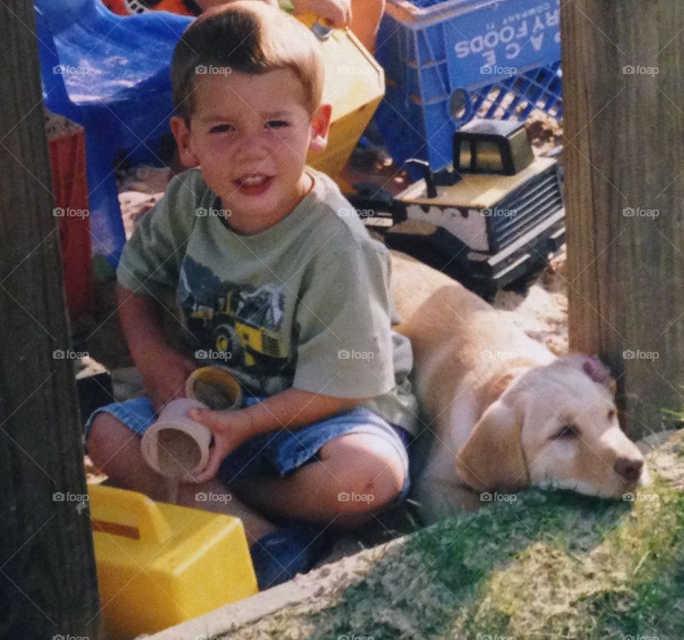 Boy playing in sandbox with puppy