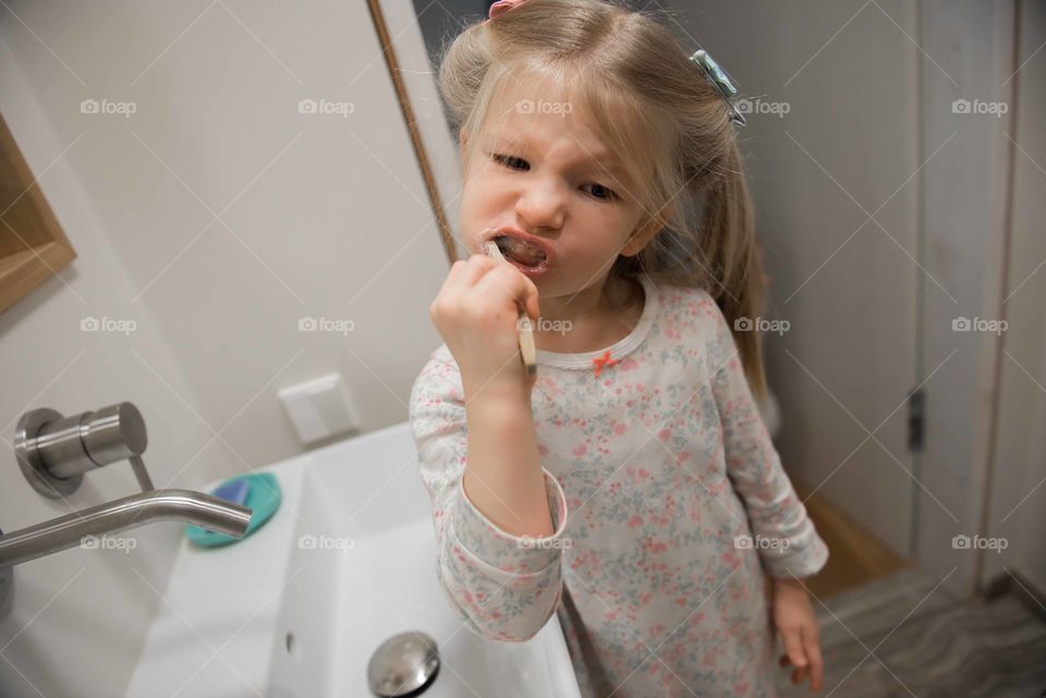 Kid little girl brushing teeth in bath