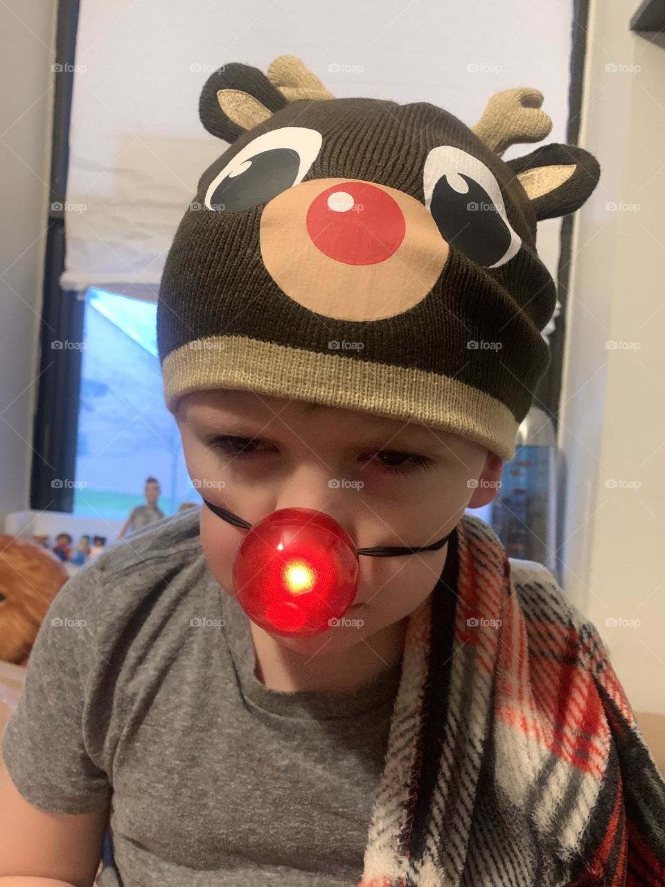 Boy with Rudolph nose looking disgusted 