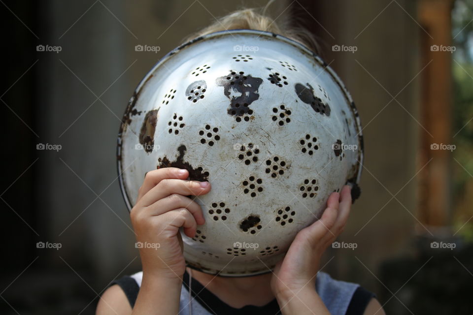 Boy covering face with strainer