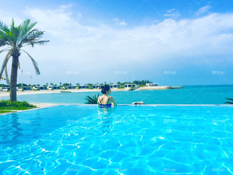 Woman in an infinity pool by the ocean at a luxury island vacation: Zaya Nurai Island Abu Dhabi 