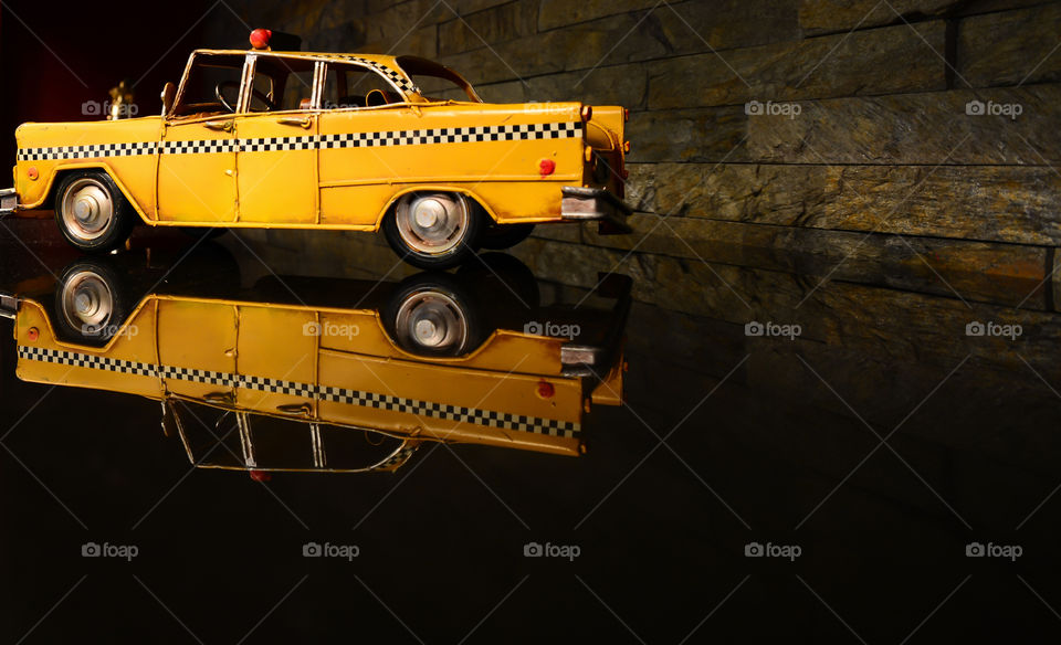yellow Metal toy car with reflection on the table
