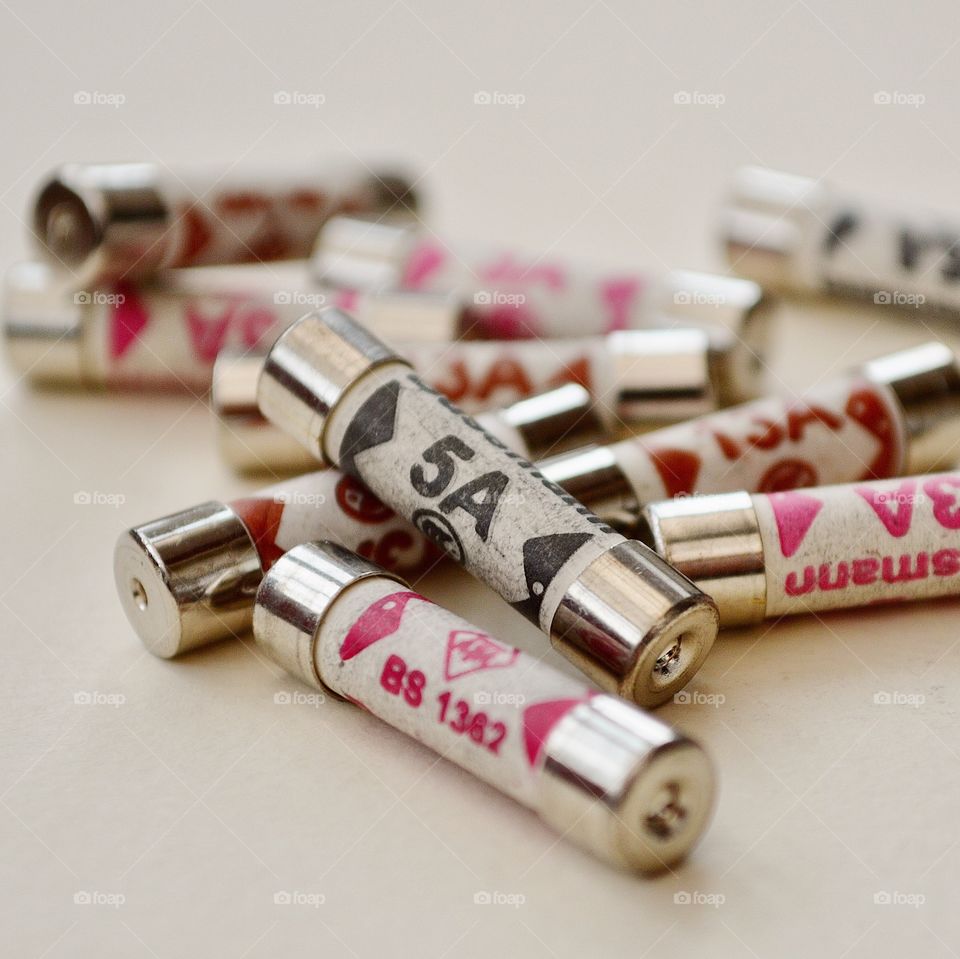 Several 5amp and 3amp fuses on a plain background. 