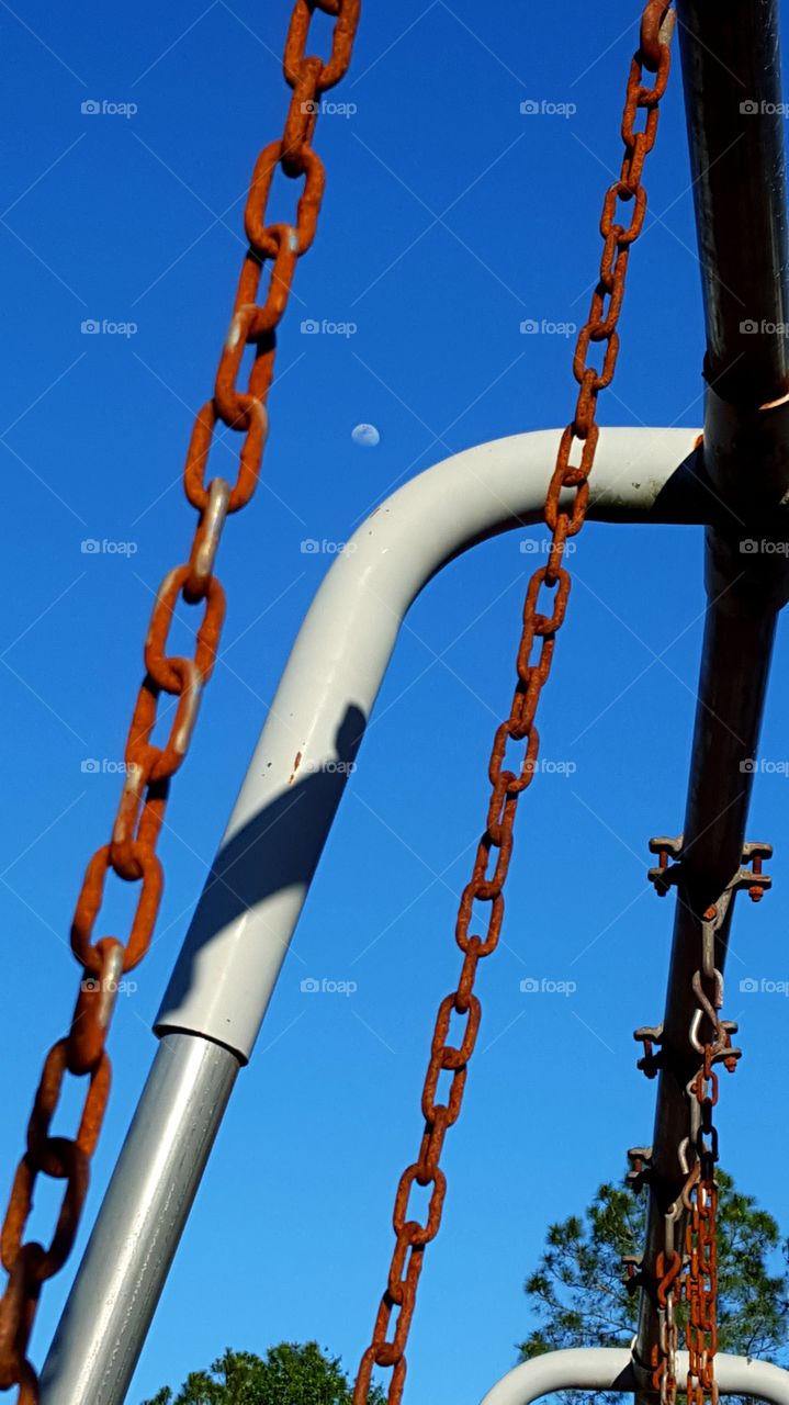 View of the moon from the seat of a swing.