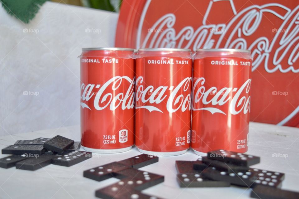 A six pack of Coca-Cola cans with dominos 