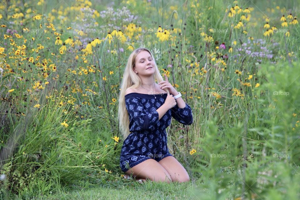 Girl with long blonde hair in summer with flowers in background