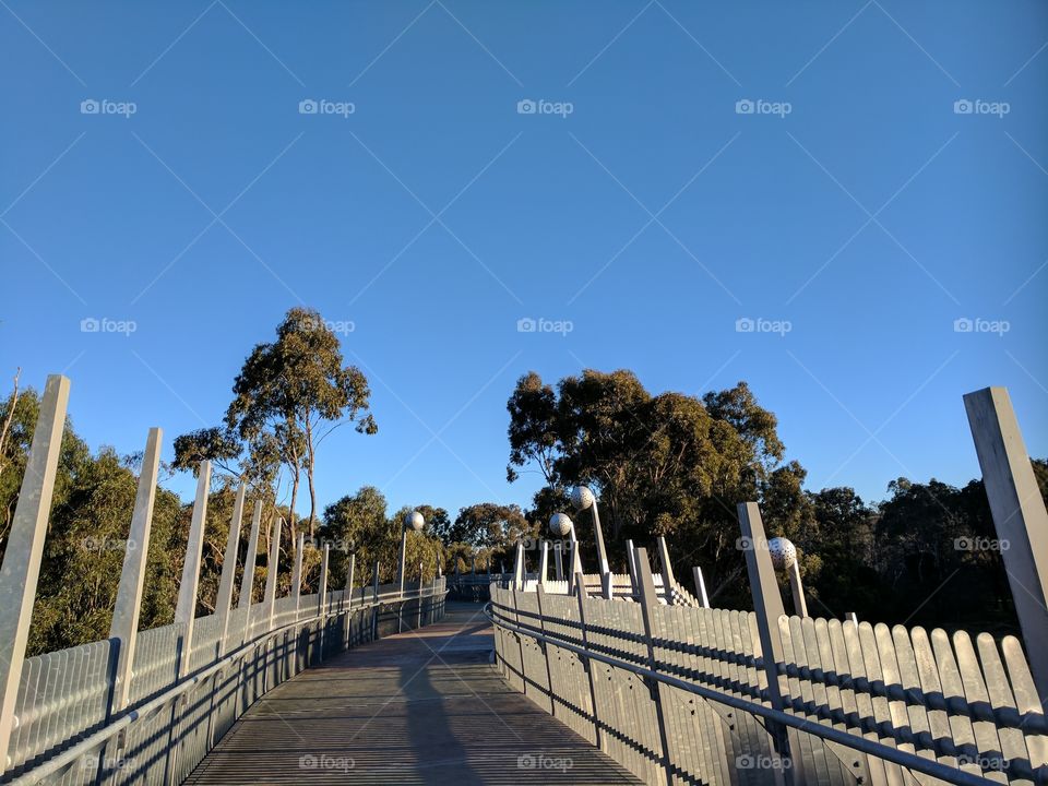 Curved Walkway bridge across river designed with small rectangular shaped columns.