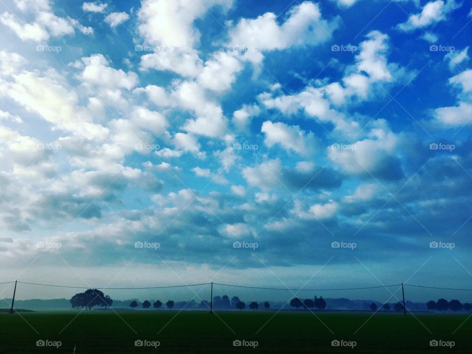 Fluffy white clouds in a deep blue sky over a rural Countryside landscape