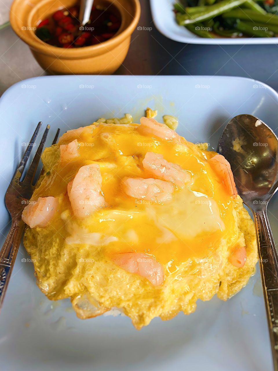 Omlette rice with shrimp for breakfast. Selective focus. Spoon and fork on each side of the dish. Street food thailand.