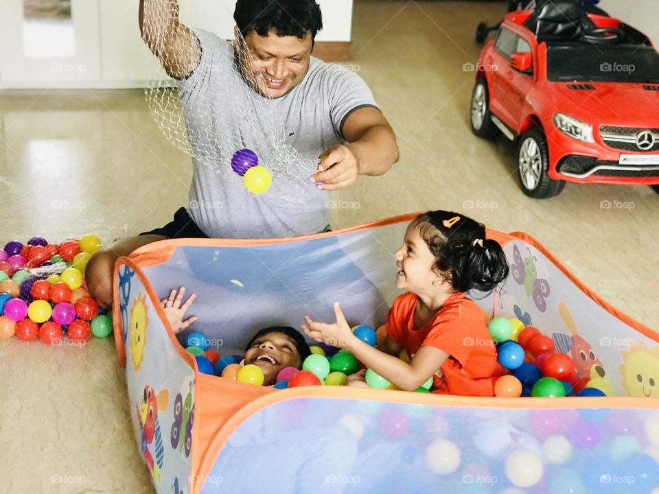 Beautiful smile of every one in the family while enjoying together at home in ball pit with kids 