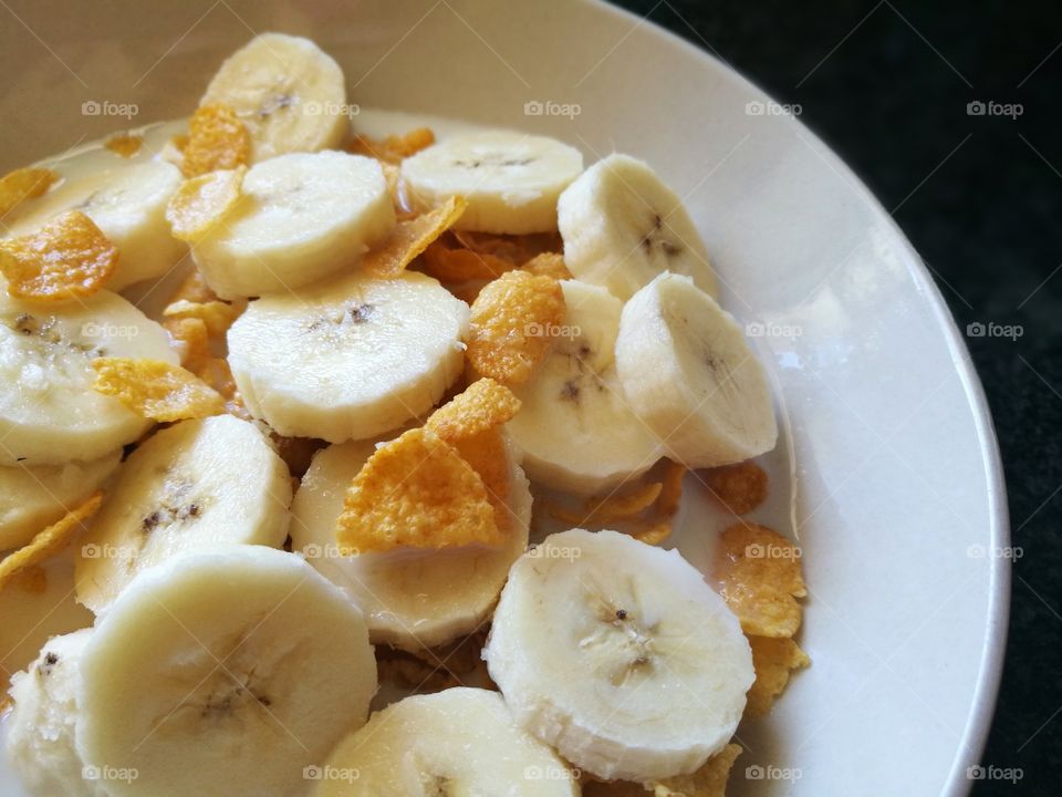 Cornflakes and banana with milk for breakfast.  Healthy food.  Cereal and banana with milk.