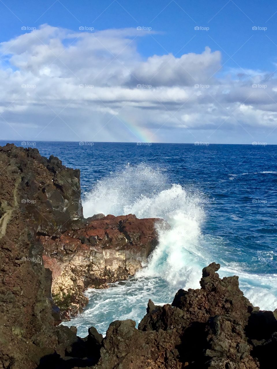 Splash in the foreground, rainbow on the horizon