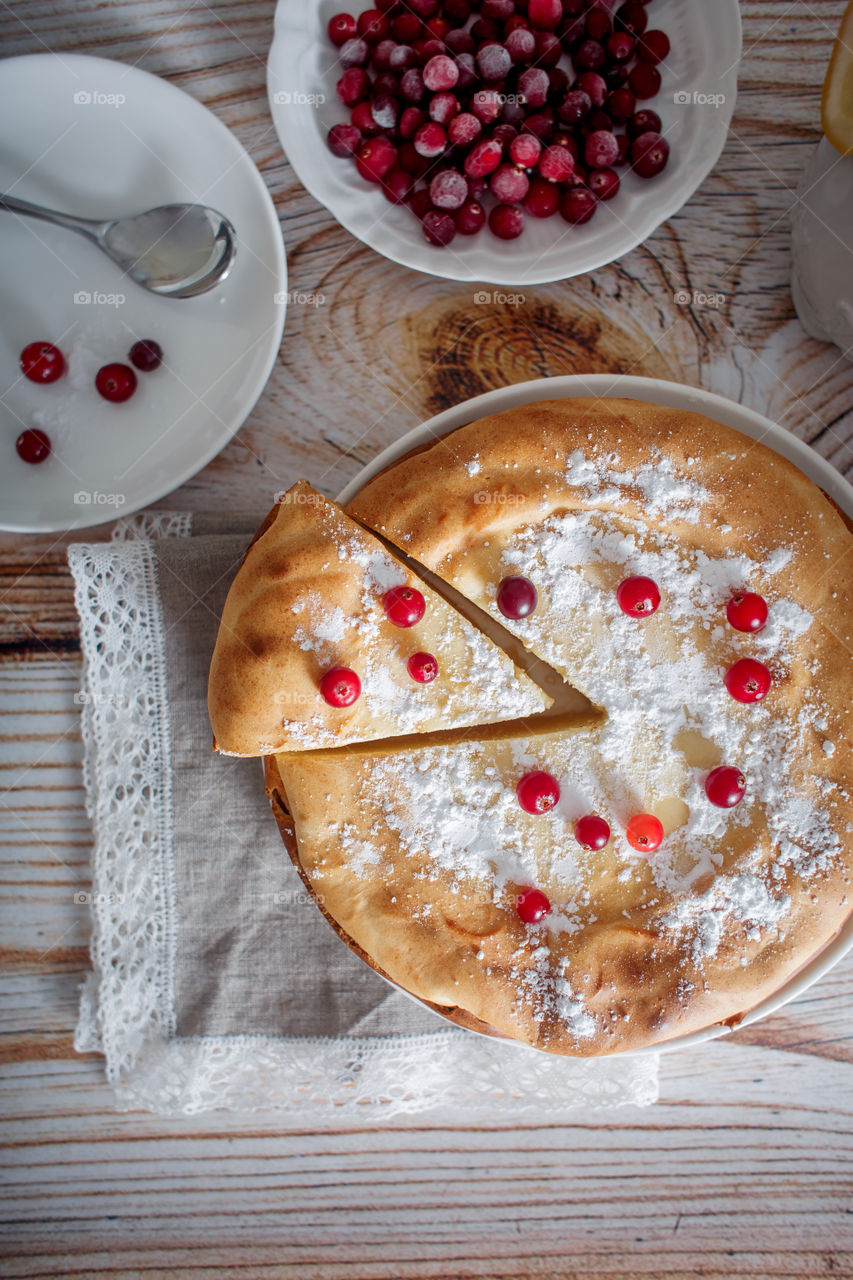 Cheesecake with cranberries and sugar on wooden background