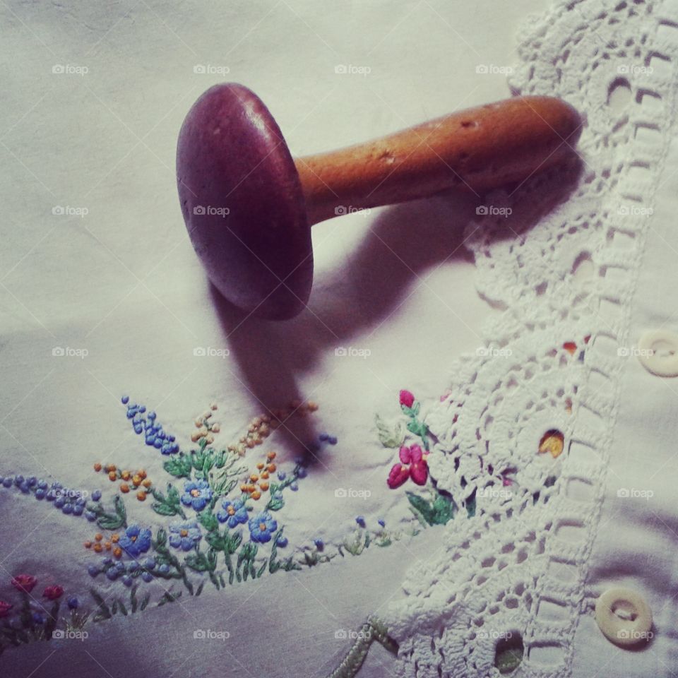 Vintage darning mushroom, with faded red top lying on old embroidered pillowcases  #vintage #embroidered  #sewing