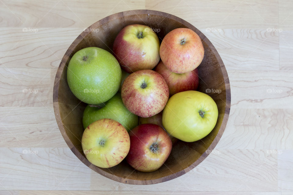 Apples different colors in wood bowl, from above 