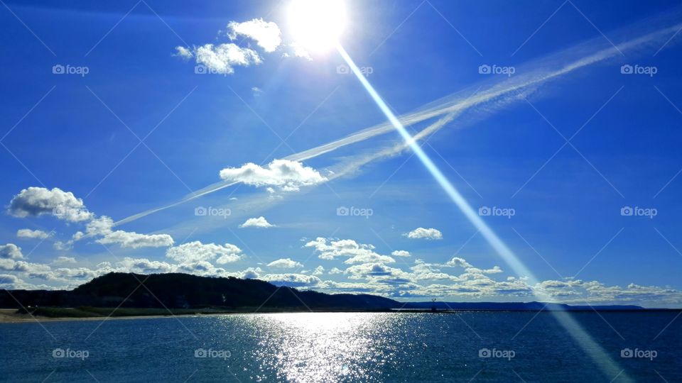 Bright sun glowing and dancing on the water in the bright blue sky