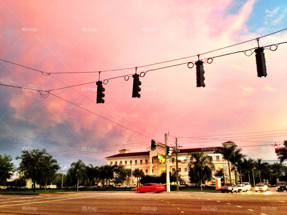 Red car rushing through traffic light at sunset