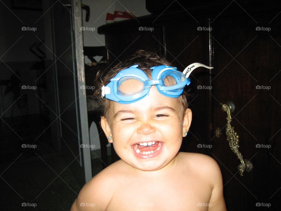 A little girl laughs while playing with swimming goggles