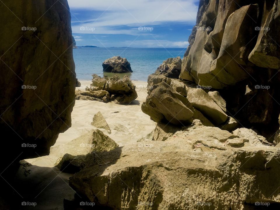 Rocks and cliff on a beach shore overlooking an ocean 