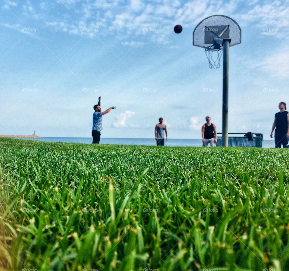 boys playing basketball, throwing basket.  Photo taken from the ground at a frog's eye view