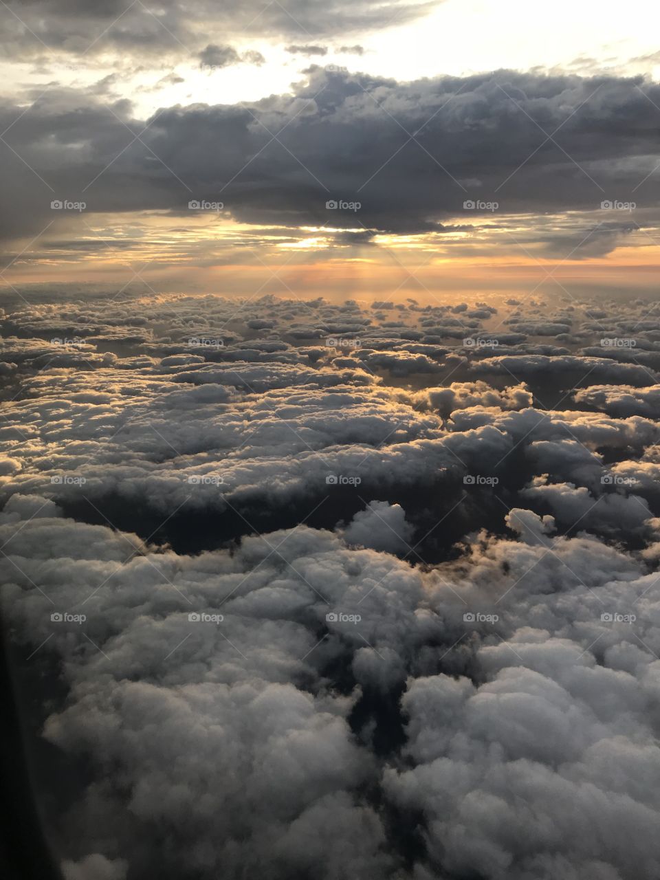 Taken from an airplane window early in the morning. Featuring rays of sun and a nice cloud bank. 