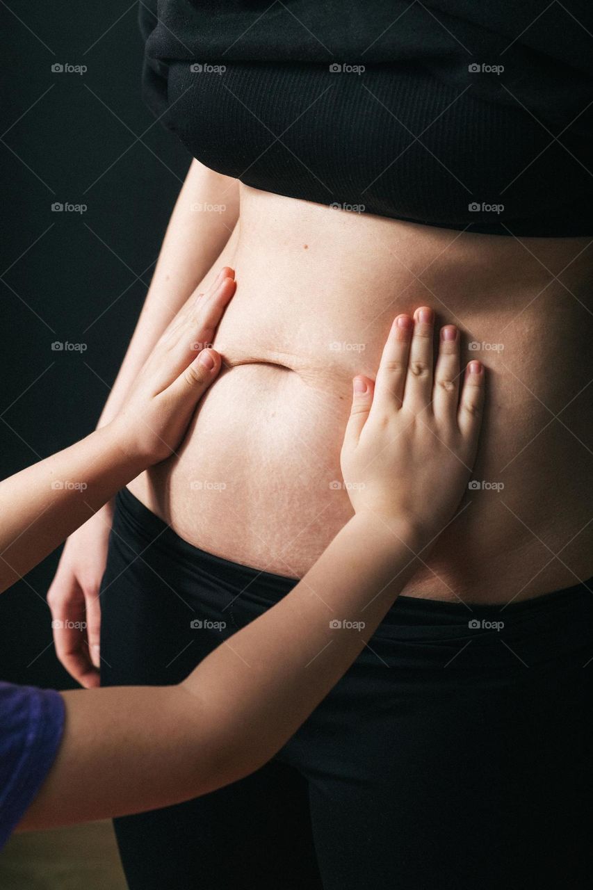 small sister touches mother's belly waiting for brother