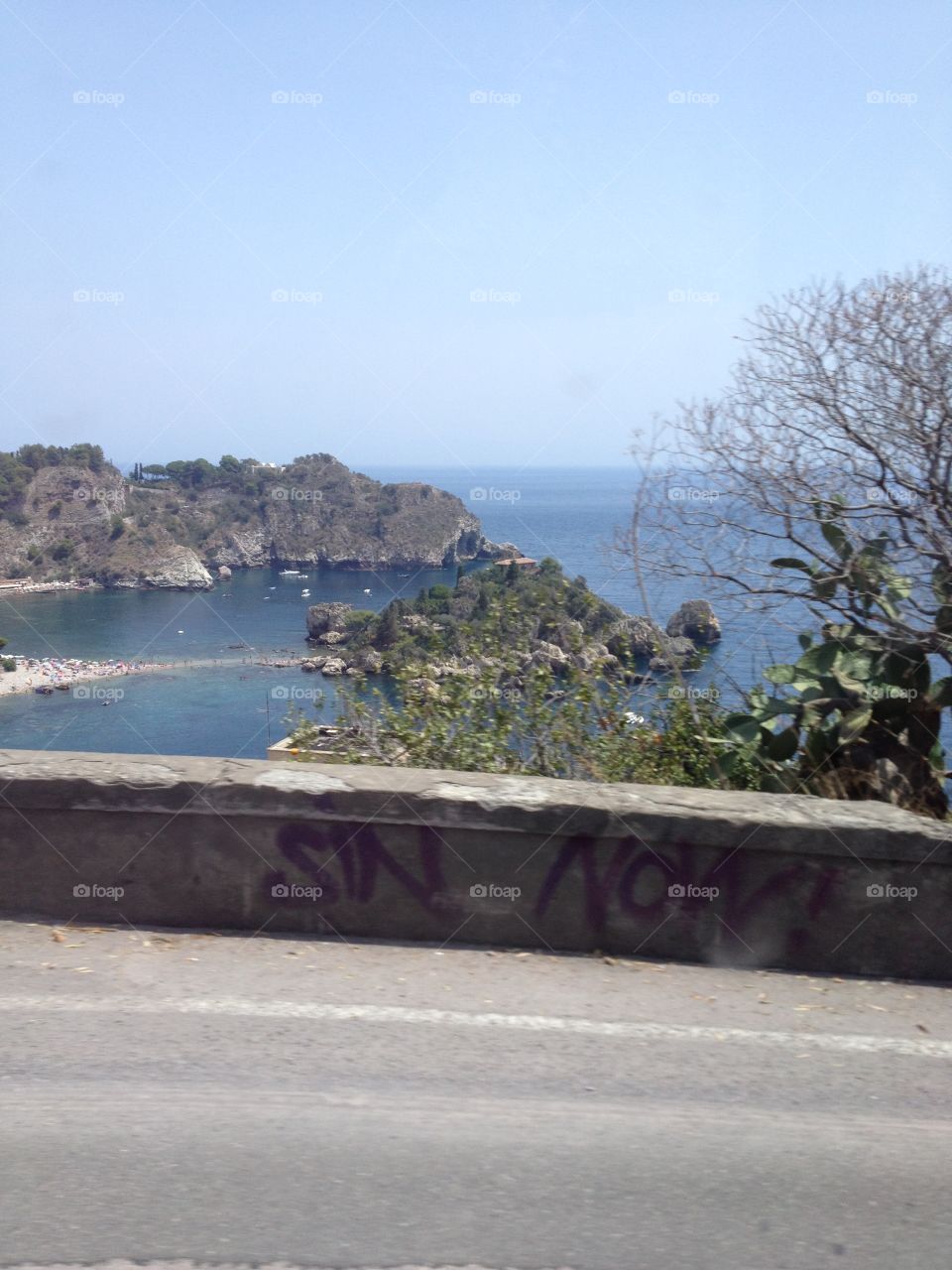 Hitting the road from Taormina towards town. Wonder what the graffiti means on the wall. Taken from the moving bus. 