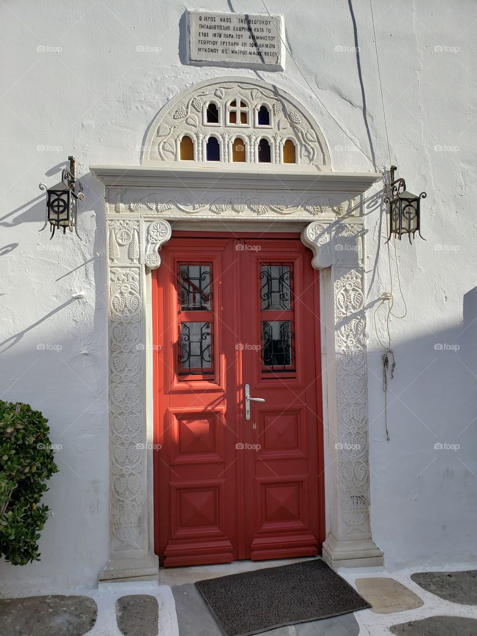 sun and shadows on beautiful red paprika door in architectural doorframe, in Mykonos, Greece.