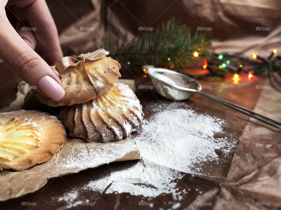 Female hand holding a fresh baked homemade Christmas cookies with sugar powder 