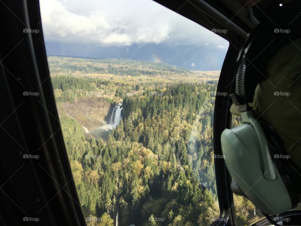 View of Snoqualmie Falls in the forest from a helicopter with helicopter headphones in the foreground. 