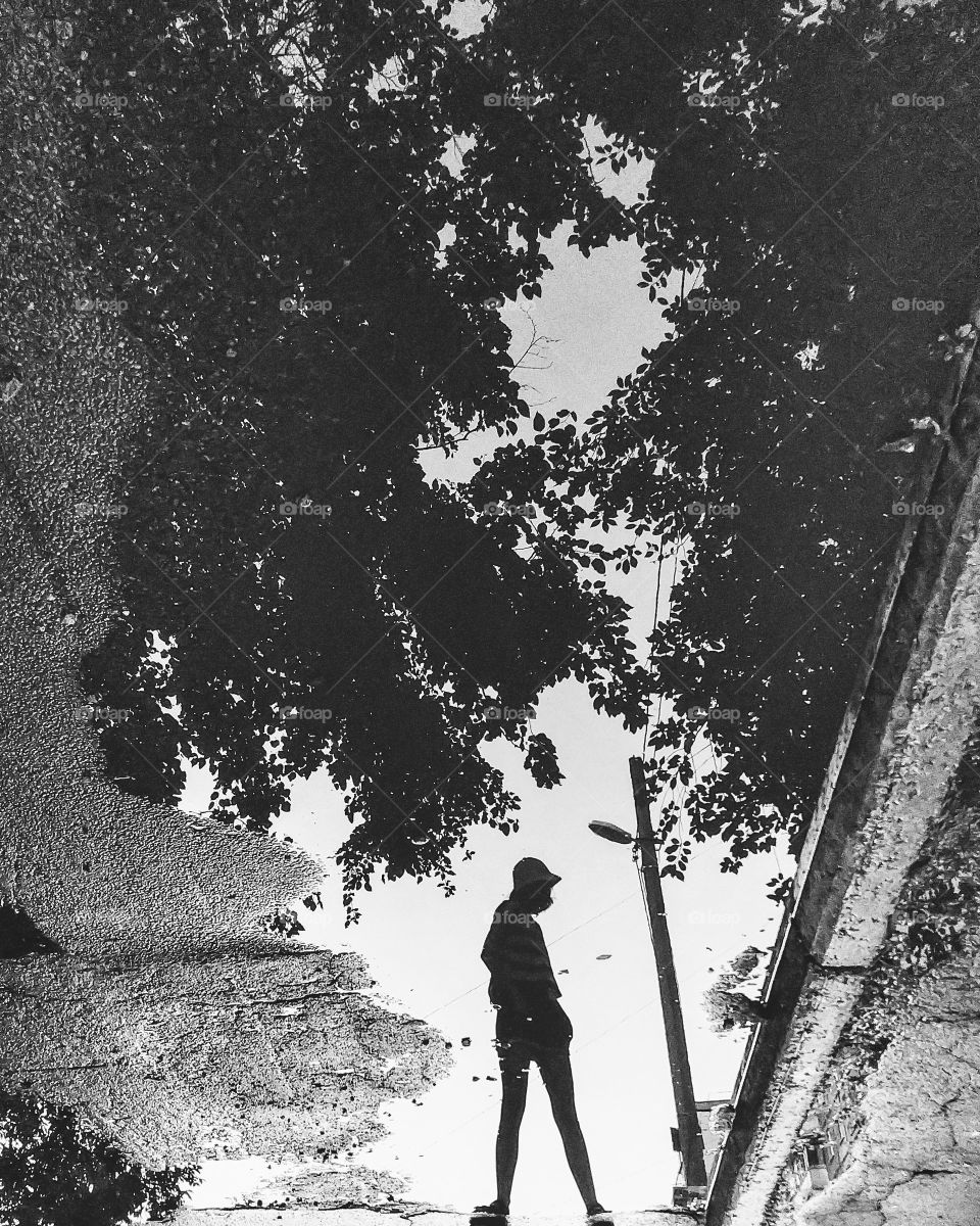 black and white reflection of a girl and trees in the water