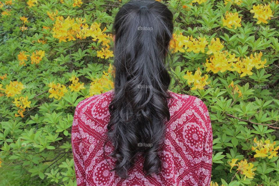 Girl with long hair standing in front of flowering bush