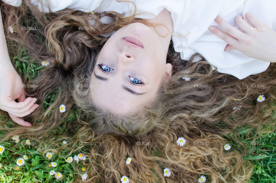 Portrait of a woman blonde with beautiful natural hair on background of daisies