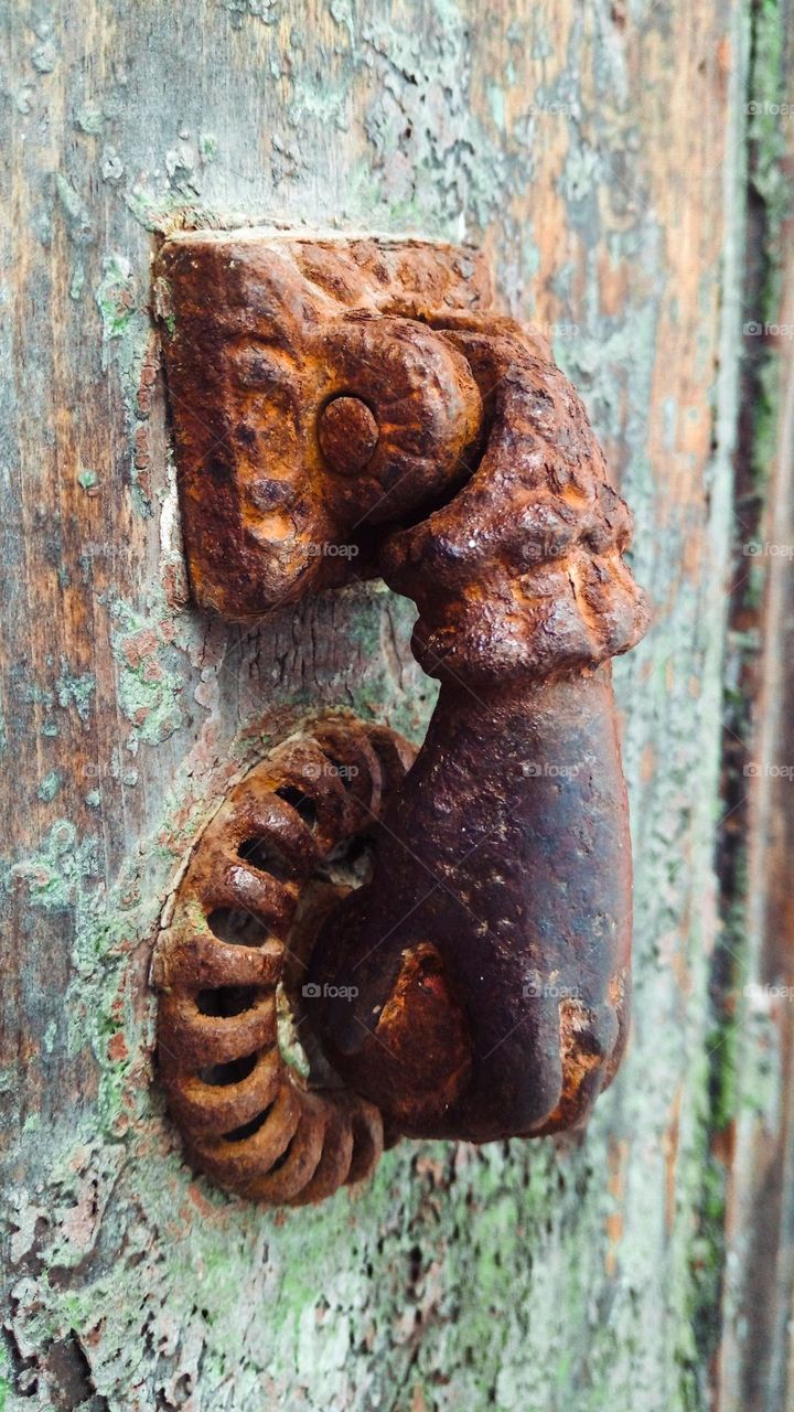 Ancient hand-shaped knob to knock on an old wooden door