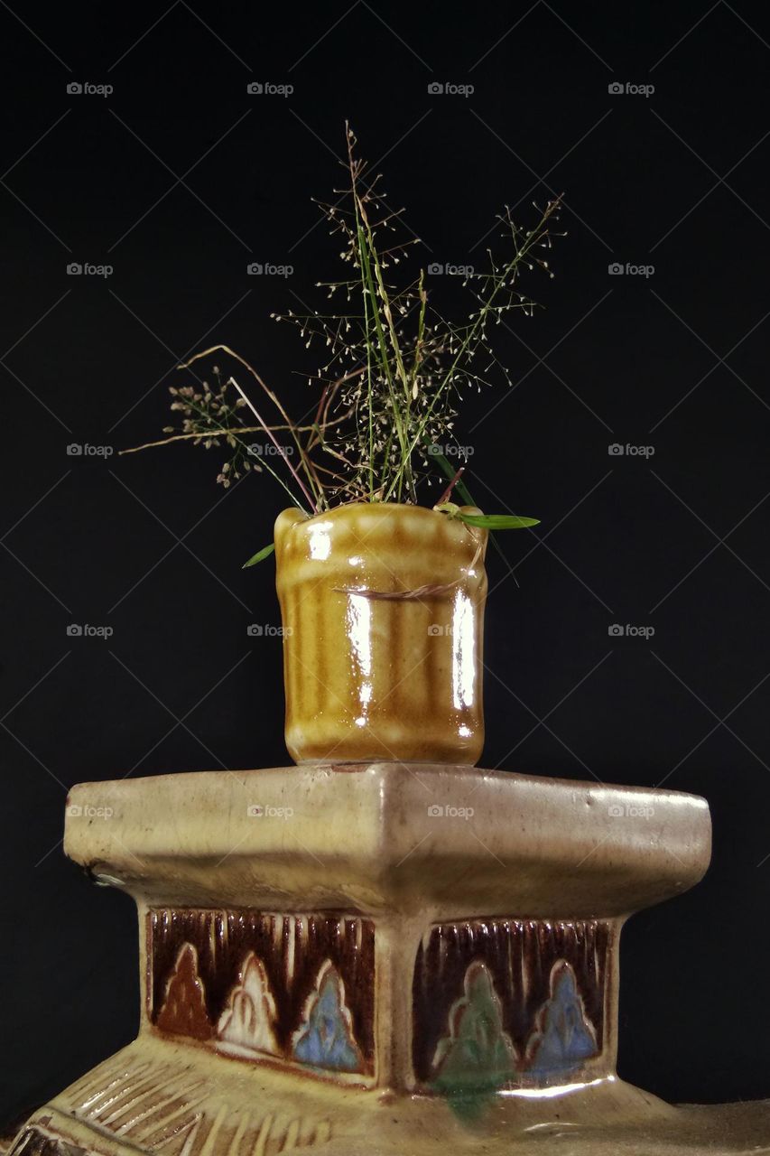 bunch of grass flowers in old ceramic vase. ceramic table
