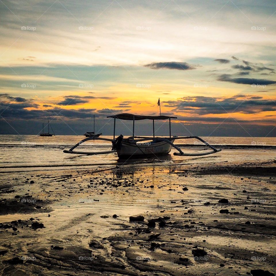 Sunset with boat over Lovina beach in Bali