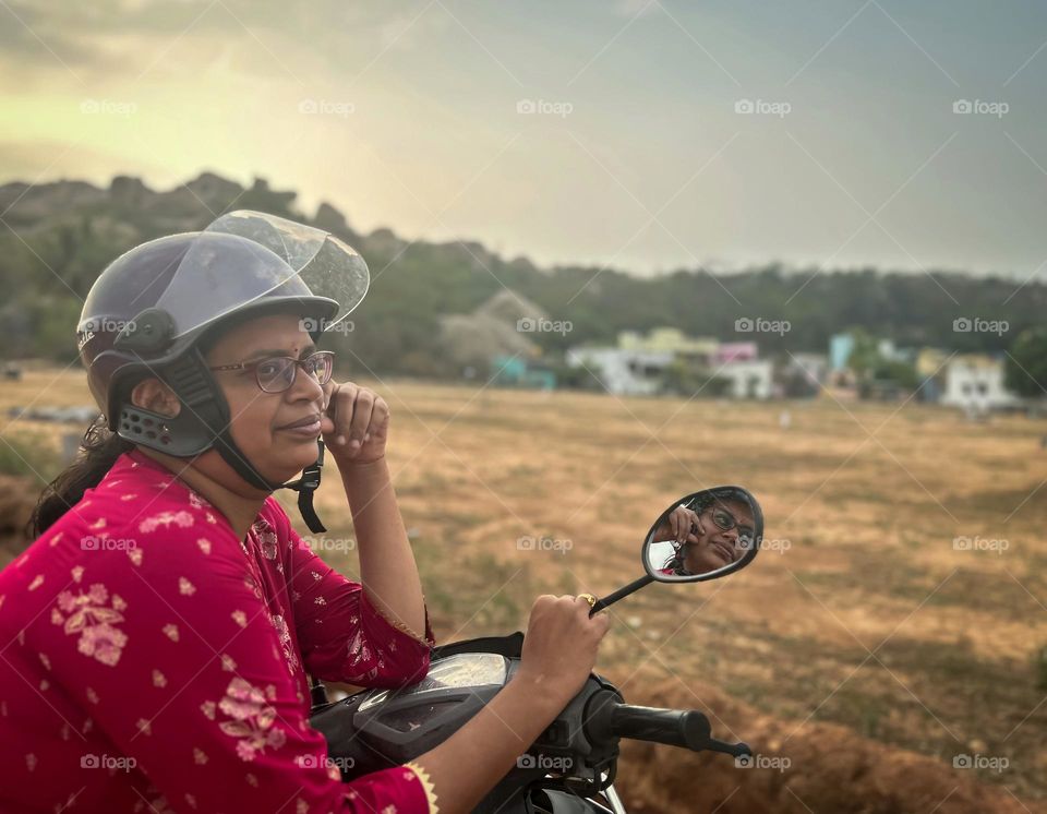 Portrait of a women sitting on her scooter with her helmet