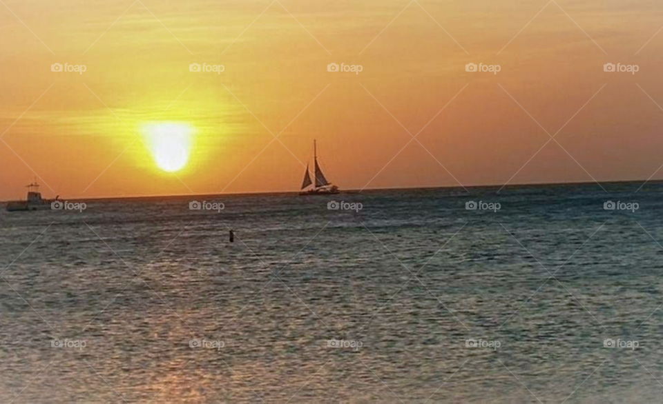 Sun setting over ocean with sailboat and fishing boat. Reflection. Sailors delight.