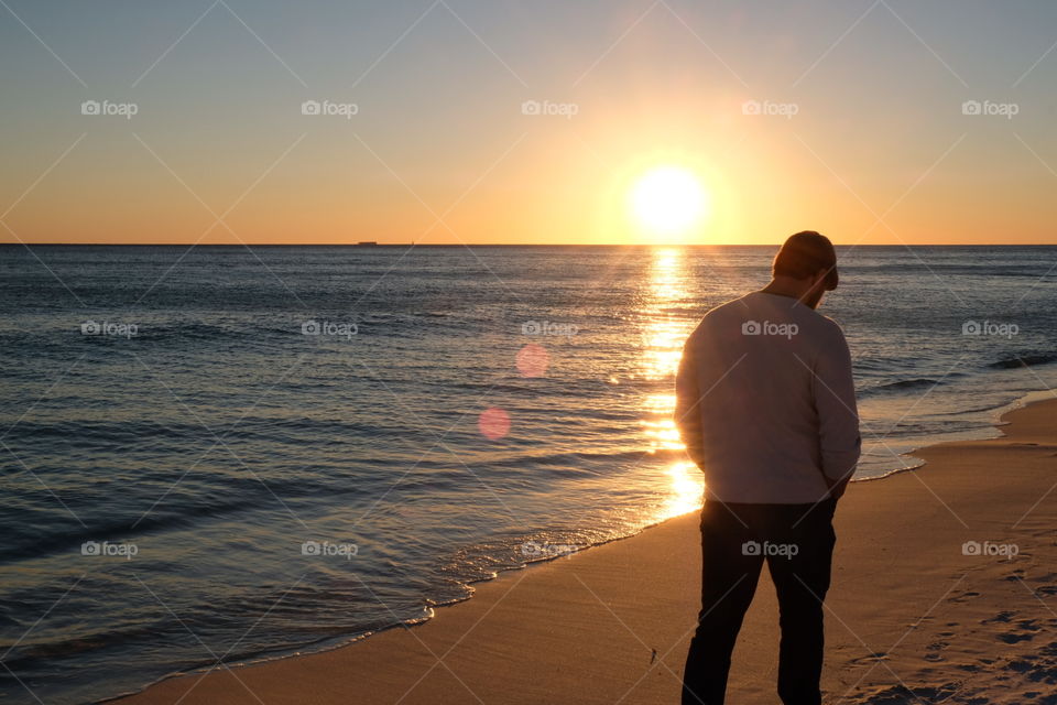 Man walking on beach at sunset